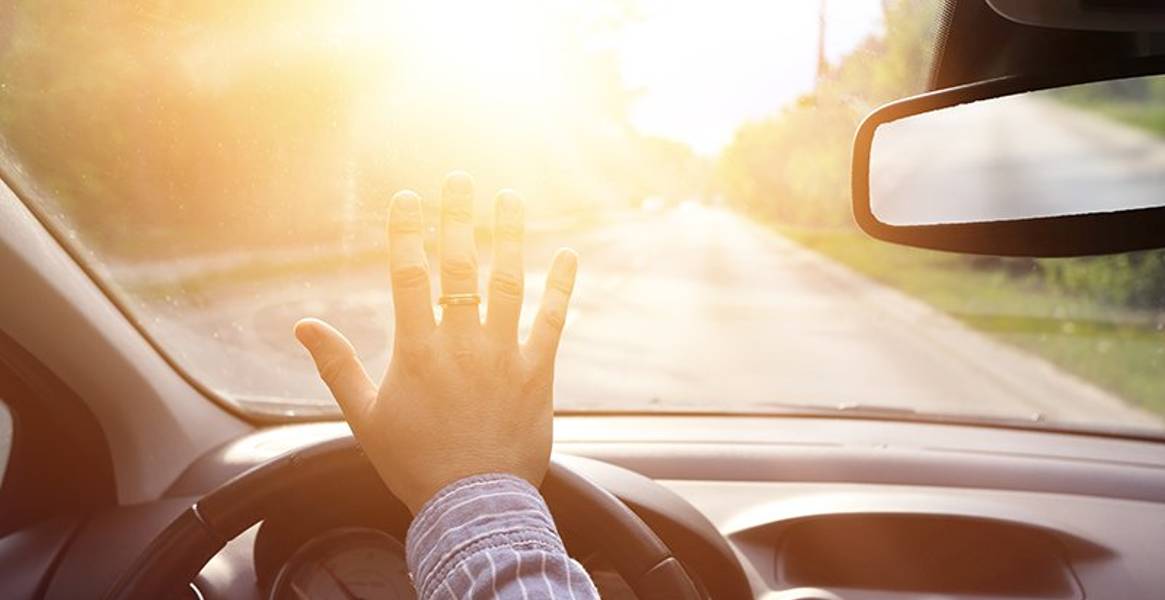 man blinded by glaring sun through windshield