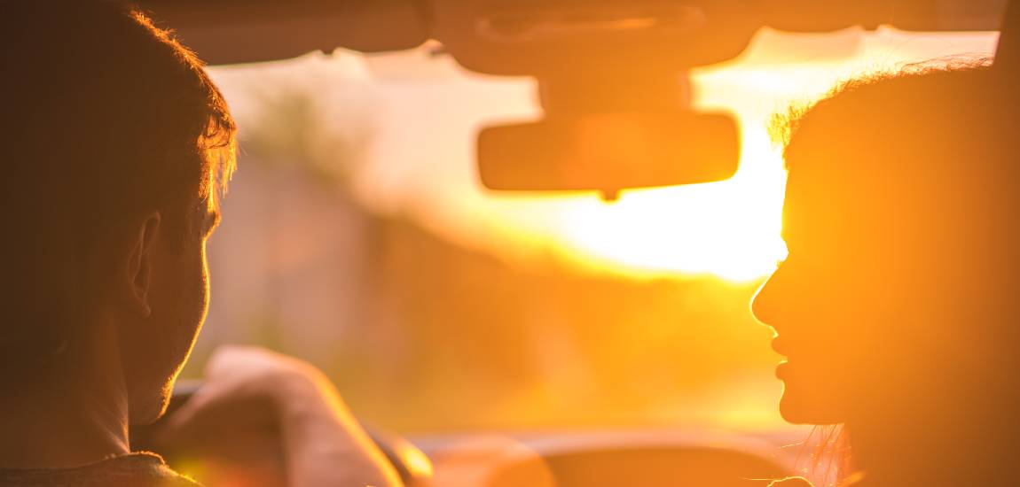 man and woman driving car with windshield sun glare