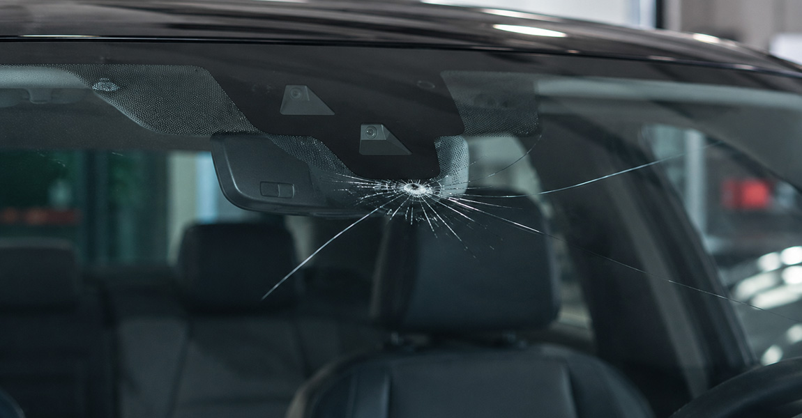 Cracked windshield on a modern vehicle with ADAS camera, illustrating replacement cost considerations