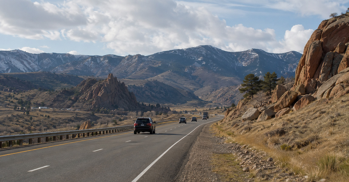 Vehicle driving on I-70 through the Colorado foothills, illustrating rock chip hazards for Denver drivers