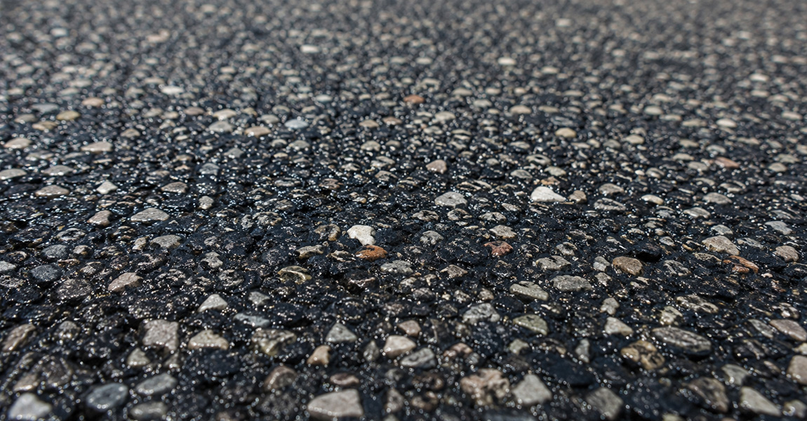 Close-up of loose gravel aggregate on a freshly chip-sealed road surface